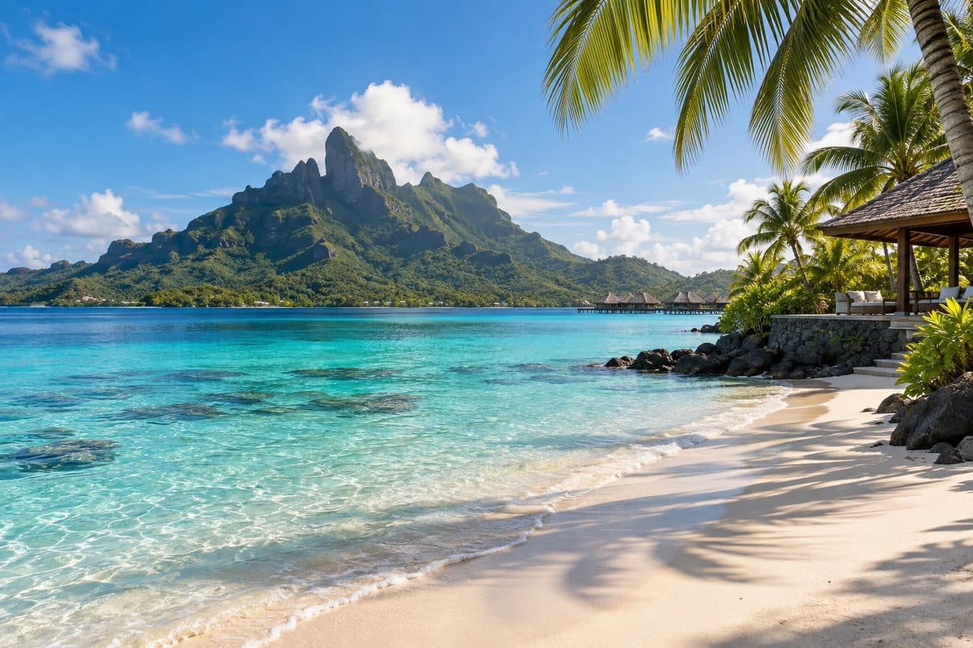 Plage de sable blanc et lagon turquoise au pied d'une île montagneuse